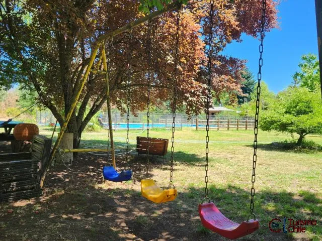 Juegos infantiles con columpios coloridos y piscina al fondo